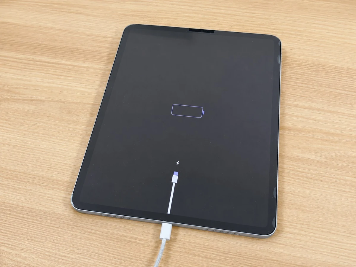Tablet displaying a low-battery charging screen while connected to a charging cable