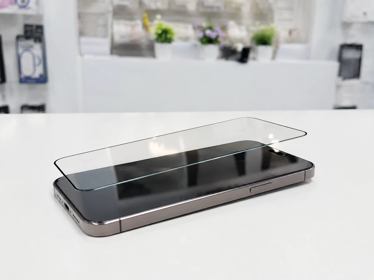Realistic in-store tempered glass screen protector displayed above a smartphone on a white counter